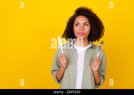 Foto di bella bruna millenaria ragazza tenere coltello folk look promo indossare camicia grigia isolato su sfondo giallo Foto Stock