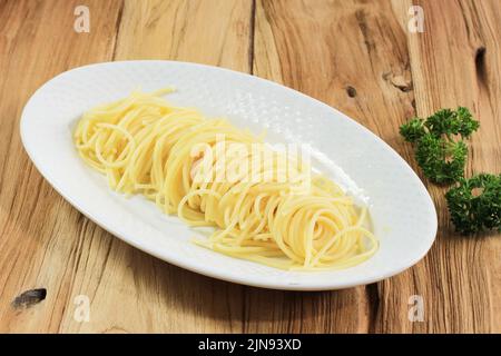 Spaghetti Pasta in un piatto ovale bianco isolato su legno di fondo, primo piano Foto Stock
