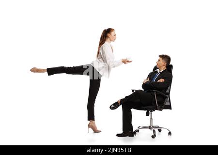 Stereotipi di genere. Due eleganti impiegati in abiti da lavoro in azione isolati su sfondo bianco. Arte, bellezza, moda e business concept Foto Stock