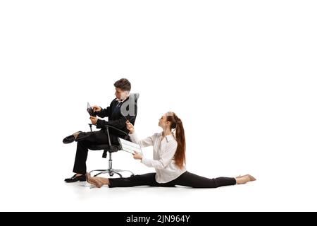 Stereotipi di genere. Due eleganti impiegati in abiti da lavoro in azione isolati su sfondo bianco. Arte, bellezza, moda e business concept Foto Stock