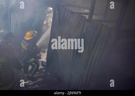 Kathmandu, Nepal. 10th ago 2022. I vigili del fuoco insieme con l'aiuto del personale dell'esercito e della polizia posano un incendio scoppiato in una fabbrica di scarpe a causa di un corto circuito a Balaju, Kathmandu. (Foto di Skanda Gautam/SOPA Images/Sipa USA) Credit: Sipa USA/Alamy Live News Foto Stock