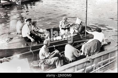Idyll im Kahn - mit Strickstrumpf unter'm Papierhut. Ausflug im Boot auf dem See, Berlino, Germania 1955. Foto Stock
