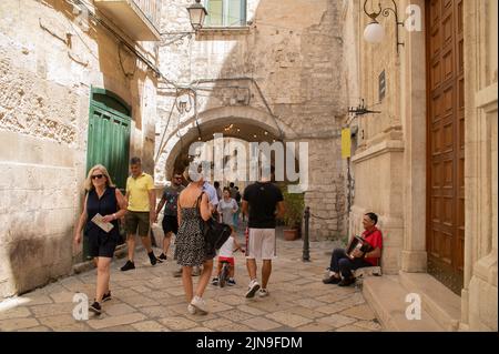 Turisti nel centro storico di Bari in estate e musicista di strada vecchia che suona la fisarmonica a due passi dalla chiesa Foto Stock
