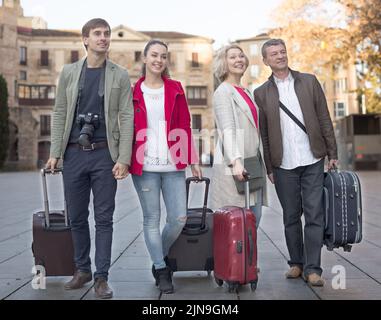 I turisti con valigie e macchina fotografica camminano lungo le strade storiche della città europea Foto Stock