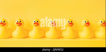 Banner giallo anatre in gomma in una linea giocattolo design arredamento scaffale. Fondo di anatra di gomma. Il giocattolo del bagno anatra di gomma di fondo giallo anatre in una fila. Riunione Foto Stock