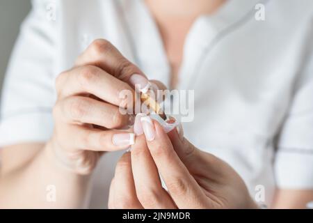 donna latina specialista in manicure, utilizzando il pennello per distribuire correttamente il gel liquido sul chiodo artificiale, per poi collocarlo sulle unghie e fare Foto Stock