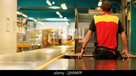 Un uomo attende i pacchi sul nastro trasportatore nel magazzino Foto Stock