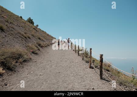 I turisti salgono all'inizio di una ripida salita fino alla cima del cono vulcanico del Vesuvio nel Golfo di Napoli. Foto Stock