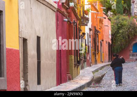 Un pulitore di strada passa le strade acciottolate di Calle Aldama al mattino presto nel centro storico della città di San Miguel de Allende, Messico. Foto Stock