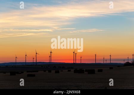 Panoramica panoramica panoramica panoramica vista panoramica nuova centrale di generazione di energia di fattoria con turbina eolica contro il caldo tramonto campo cielo. Zero pulito e sostenibile Foto Stock