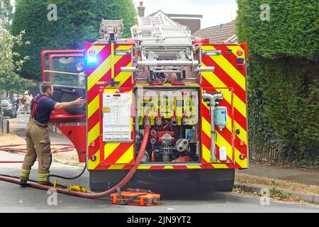 Essex Fire and Rescue Service at house building on Fire close up back view vigili del fuoco brigate valvole del motore con raccordo per tubi flessibili e pompiere Inghilterra UK Foto Stock