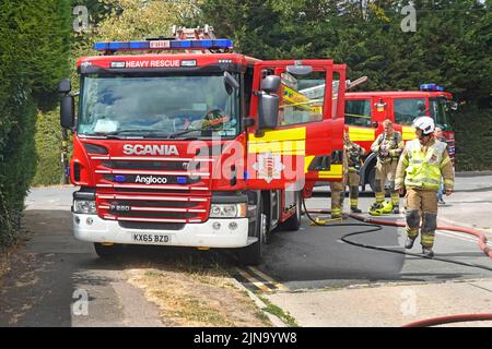 Servizio antincendio e di soccorso Essex vigili del fuoco vigili del fuoco presenti in casa con due motori antincendio e vigili del fuoco in via residenziale Inghilterra Regno Unito Foto Stock