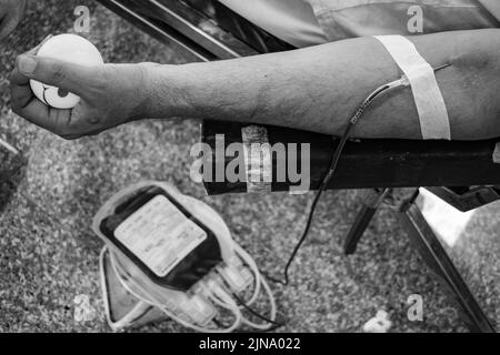 Donatore di sangue al campo di donazione di sangue tenuto con una palla rimbalzante in mano al Tempio Balaji, Vivek Vihar, Delhi, India, Image for World Blood Donor da Foto Stock