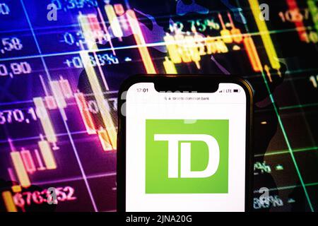 KONSKIE, POLONIA - 09 agosto 2022: Smartphone che mostra il logo della società Toronto Dominion Bank sullo sfondo del diagramma di borsa Foto Stock