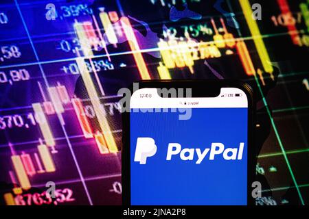 KONSKIE, POLONIA - 09 agosto 2022: Smartphone che mostra il logo della società PayPal sullo sfondo del diagramma di borsa Foto Stock