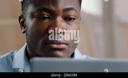 Serio giovane uomo d'affari afro-americano programmatore scrivere sul computer a casa ufficio concentrato millennial sicuro di uso computer portatile Foto Stock