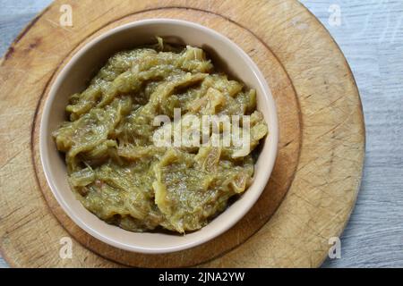 Una ciotola di rabarbaro cotto in una ciotola di ceramica marrone su un tagliere di legno inghilterra gran Bretagna UK Foto Stock