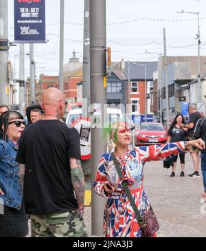 Una donna che indossa un abito da Union jack si trova presso un lampione durante il Blackpool, Lancashire, Regno Unito Agosto 6 2022 Blackpool Rebellion Punk Festival Foto Stock