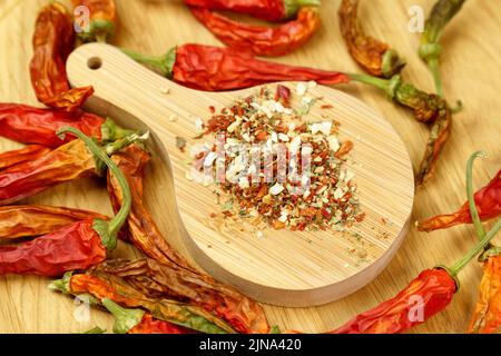 Peperoncini che cadono, condimento delle spezie, peperoni rossi secchi su un tavolo di legno, fondo, paprika secca. Messa a fuoco selettiva Foto Stock