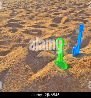Primo piano di due pale in plastica nella sabbia su una spiaggia, Italia Foto Stock