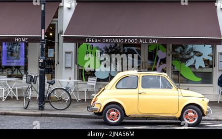 Londra, Regno Unito - 11 marzo 2022: Fiat 500 retrò parcheggiata all'esterno di un bar biologico nel cuore di Notting Hill, Londra. Questo quartiere è molto popolare Foto Stock