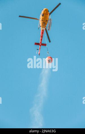 Elicottero che trasporta acqua per spegnere un incendio boschivo Foto Stock