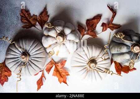 Vista dall'alto delle decorazioni ornamentali in ceramica di zucca su un tavolo con foglie autunnali Foto Stock