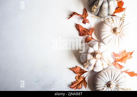 Vista dall'alto delle decorazioni ornamentali in ceramica di zucca su un tavolo con foglie autunnali Foto Stock