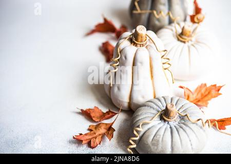 Vista dall'alto delle decorazioni ornamentali in ceramica di zucca su un tavolo con foglie autunnali Foto Stock