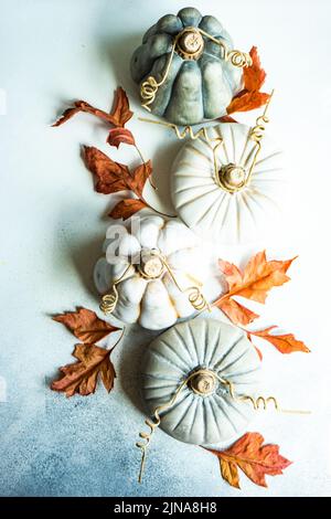 Vista dall'alto delle decorazioni ornamentali in ceramica di zucca su un tavolo con foglie autunnali Foto Stock