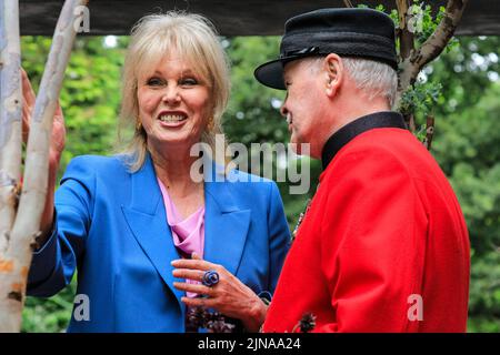 L'attrice Joanna Lumley sorridendo, da vicino, si pone con il pensionato Chelsea John Gallagher nelle sue uniformi rosse, Chelsea Flower Show 2022 Foto Stock