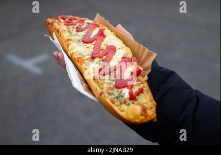 Maneggio delizioso panino chiamato Zapiekanka vicino al campo da cibo di strada di Okraglak sulla Piazza Ebraica di Plac Nowy, Kazimierz, Cracovia, Polonia. Foto Stock