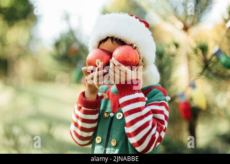 Natale nel mese di luglio. Bambino in attesa di Natale in legno in estate. Ritratto di ragazzo decorazione albero di natale. Vacanze invernali e concetto di persone. Buon Natale e buone feste Foto Stock