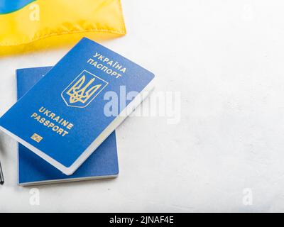 Su sfondo bianco si trova una piccola bandiera gialla e blu dell'Ucraina e due passaporti biometrici ucraini. Patriottismo, libertà, indipendenza, wa Foto Stock