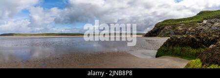 Panorama della spiaggia di Maghera di sabbia dorata con rocce ricoperte di alghe e scogliere in primo piano Foto Stock