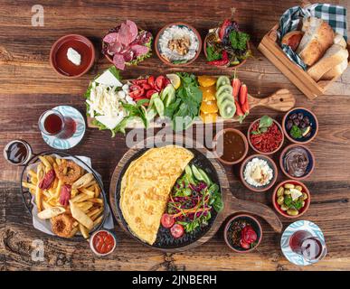 Tradizionale colazione turca servita con tradizionale tè turco su tavolo in legno. La colazione o il brunch al tavolo pieno di ogni tipo di delizioso delicato Foto Stock
