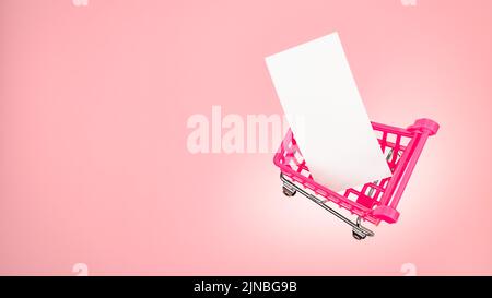 Carrello per il mercato dei piccoli carrelli con etichetta bianca in carta bianca su sfondo rosa. Il carrello di vendita rosa è vuoto chiaro della scheda del messaggio. Rosa Foto Stock