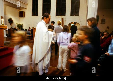 La Congregazione parte dopo la Messa la vigilia di Natale, Cheam Surrey Inghilterra di San Cecilia Foto Stock