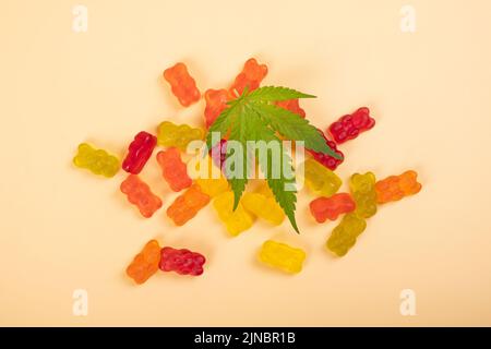 caramelle di gelatina di thc, dolci di cannabis e foglia verde su sfondo giallo. Foto Stock