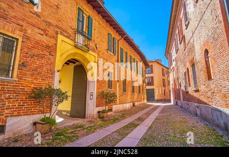 La stretta strada medievale italiana con edifici storici in mattoni nel centro di Pavia Foto Stock