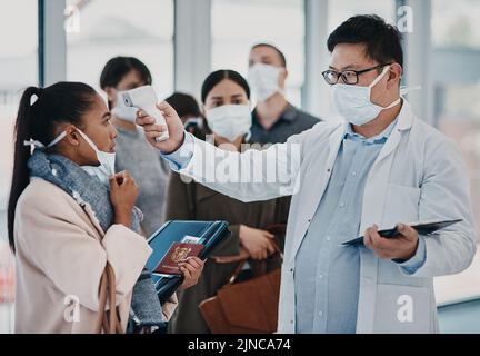 Un operatore sanitario che esegue test di temperatura elevata in aeroporto utilizzando un termometro a infrarossi. Professionista medico che fa un controllo di coronavirus su un Foto Stock