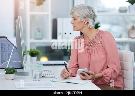 Il multitasking vi consente di risparmiare molto tempo in ufficio. Una donna matura che lavora nel suo ufficio. Foto Stock