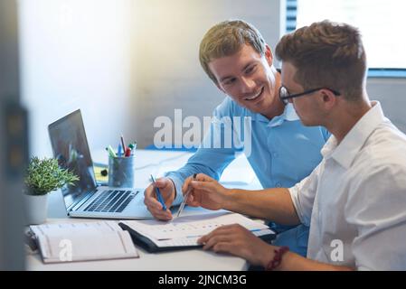 Una buona comunicazione è fondamentale per raggiungere un obiettivo comune: Due bei giovani imprenditori che lavorano insieme nel loro ufficio. Foto Stock