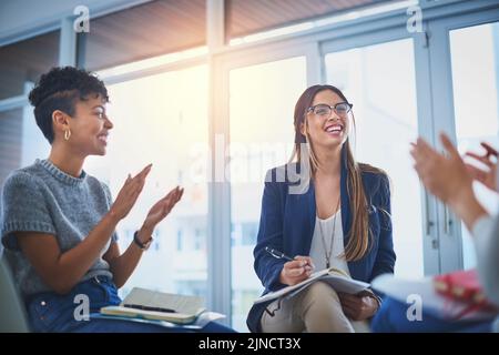 Questo è ciò che voi chiamate un ambiente produttivo: Un gruppo di giovani imprenditrici che dà un applauso ai loro colleghi durante una riunione sul lavoro. Foto Stock