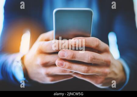 Tenere il passo con tutte le ultime tendenze del mercato. Un uomo d'affari irriconoscibile utilizzando il suo cellulare al lavoro. Foto Stock