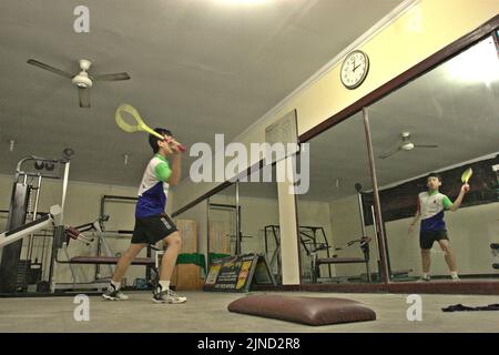 Un giovane atleta di badminton sta praticando vari colpi davanti ad un grande specchio al randello di badminton di Jaya Raya a Jakarta, Indonesia. Foto Stock