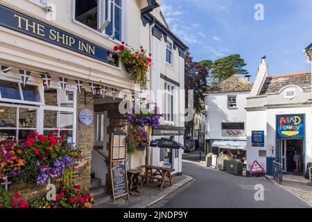 Una scena di strada con colorate esposizioni floreali fuori del 16th ° secolo Ship Inn, un pub storico a Fowey, Cornovaglia. Foto Stock