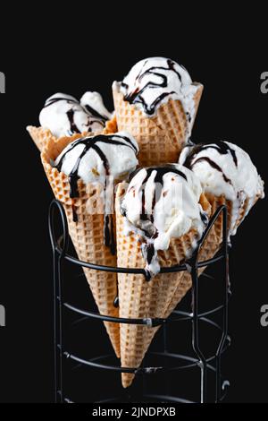 Coni di gelato alla vaniglia fatto in casa con cioccolato su sfondo scuro Foto Stock