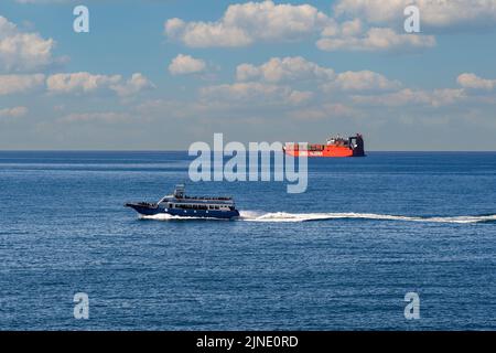 Una barca turistica e una nave container della linea Messina, una compagnia di navigazione con sede a Genova, all'orizzonte del mare, Nervi, Genova, Liguria Foto Stock