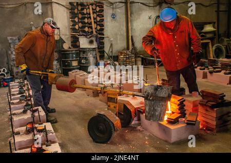 Lavoratori di fonderia che versano metallo fuso in stampi in una piccola fonderia di famiglia a Perth, Australia Occidentale Foto Stock